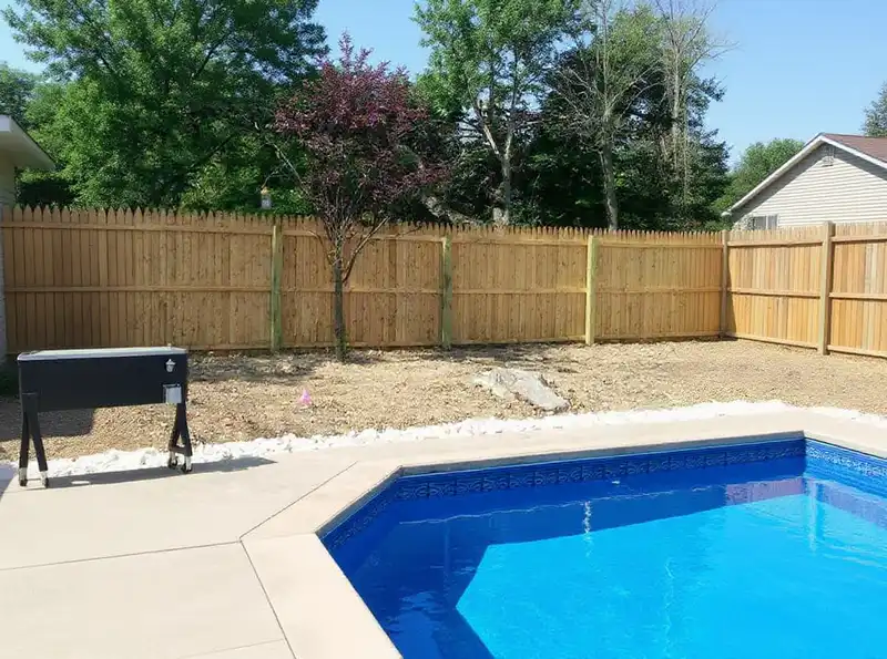 Six-foot solid board privacy fence with dog-ear pickets in a suburban yard