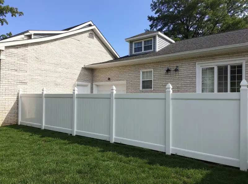 White vinyl privacy fence with tongue-and-groove panels along a residential property line